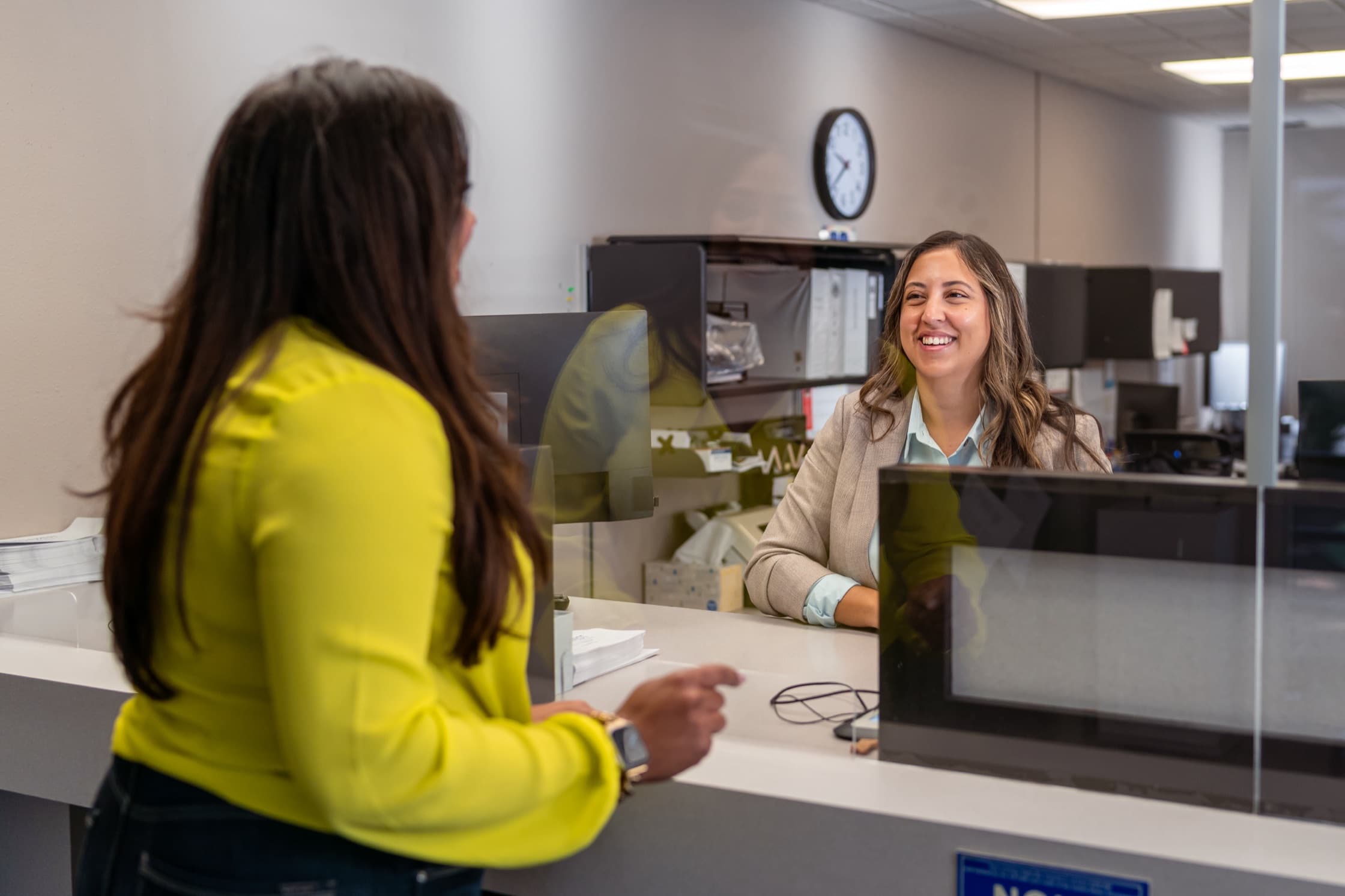 A clerk smiling at a customer across the service window
